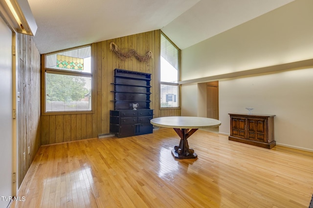 foyer entrance with vaulted ceiling, plenty of natural light, and wooden walls