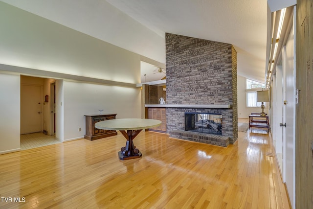 unfurnished living room featuring ceiling fan, a fireplace, high vaulted ceiling, and light hardwood / wood-style flooring