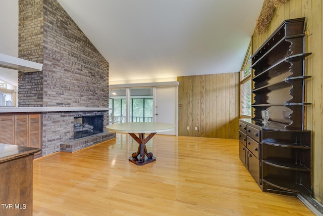 unfurnished living room featuring a fireplace, light hardwood / wood-style flooring, plenty of natural light, and wooden walls