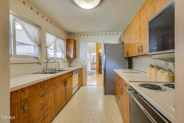 kitchen with stainless steel fridge, dishwashing machine, a textured ceiling, sink, and range with electric stovetop