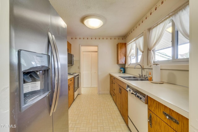 kitchen with dishwasher, sink, a textured ceiling, electric range oven, and stainless steel fridge with ice dispenser