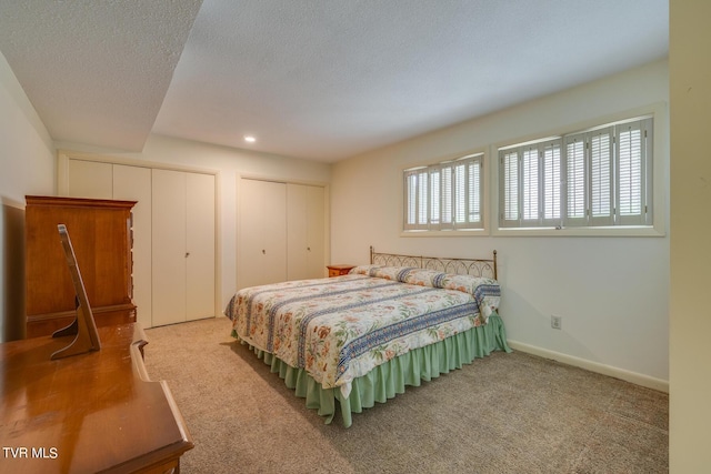 carpeted bedroom with a textured ceiling and two closets