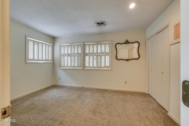 carpeted empty room featuring a textured ceiling