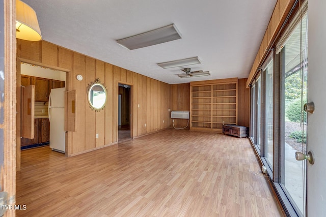 interior space featuring ceiling fan, wood walls, and light hardwood / wood-style flooring