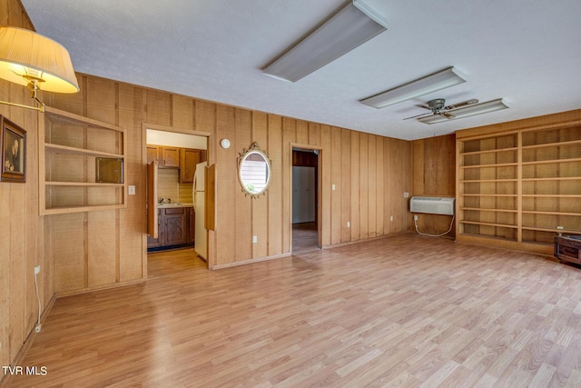 unfurnished living room featuring light hardwood / wood-style flooring, built in features, and wood walls