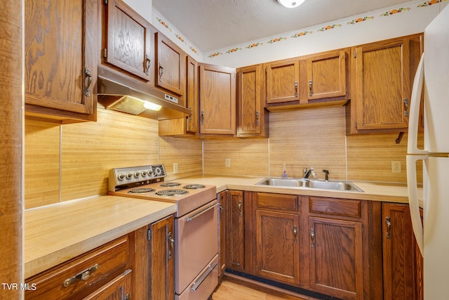 kitchen featuring sink, electric range oven, white fridge, a textured ceiling, and decorative backsplash