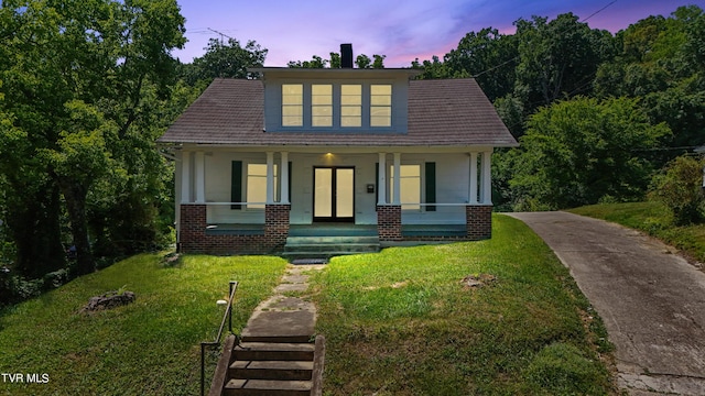 view of front of property with a porch and a yard