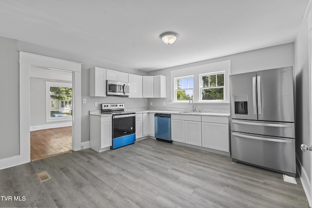 kitchen with sink, light hardwood / wood-style flooring, stainless steel appliances, and white cabinets