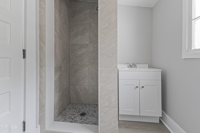 bathroom with tiled shower and vanity