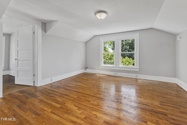 additional living space with vaulted ceiling and wood-type flooring