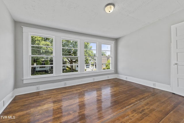 spare room with plenty of natural light, dark wood-type flooring, and a textured ceiling