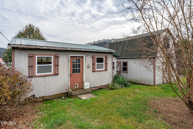 rear view of house featuring an outdoor structure and a yard