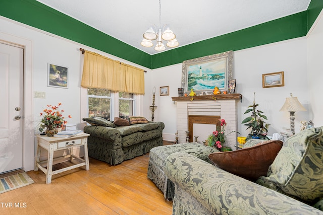 living room with light hardwood / wood-style floors, a brick fireplace, and a notable chandelier