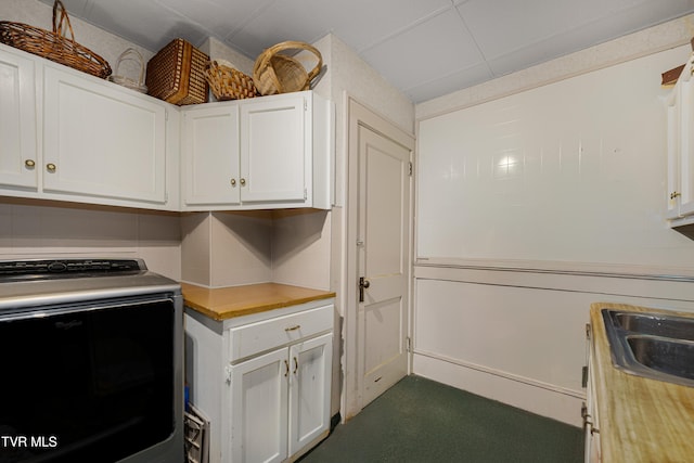 kitchen with white cabinets, dark carpet, and washer / dryer