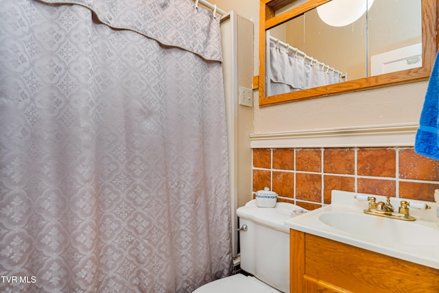 bathroom with vanity, toilet, and tasteful backsplash