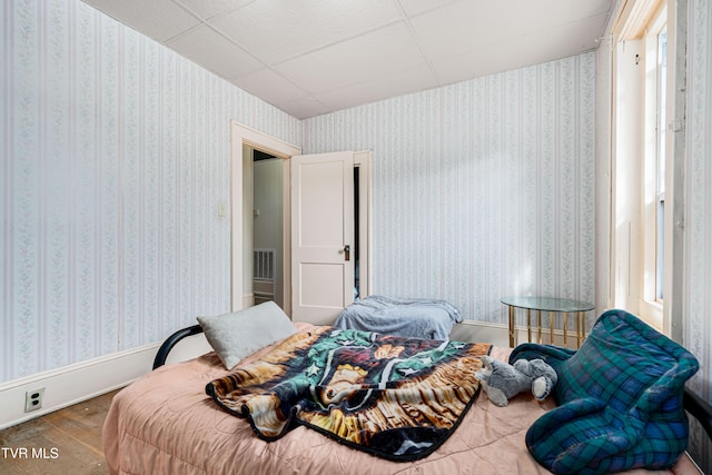 bedroom with a drop ceiling and wood-type flooring