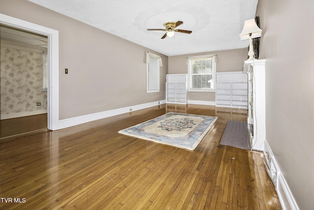 unfurnished living room featuring ceiling fan, dark hardwood / wood-style flooring, and a textured ceiling