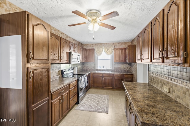 kitchen with electric range, backsplash, ceiling fan, and sink