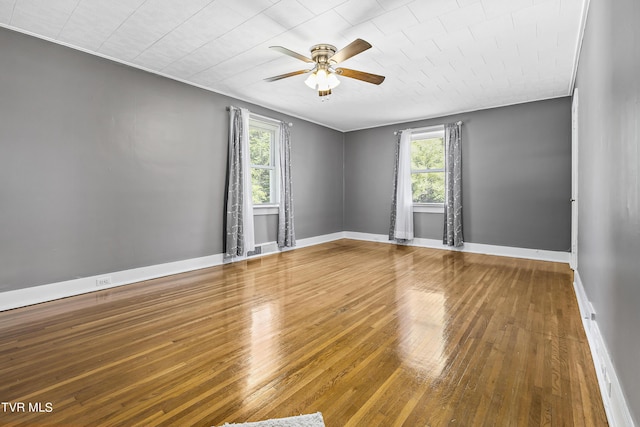 empty room featuring wood-type flooring, a wealth of natural light, and ceiling fan