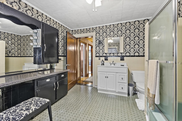 bathroom featuring an enclosed shower, toilet, vanity, tile walls, and ornamental molding