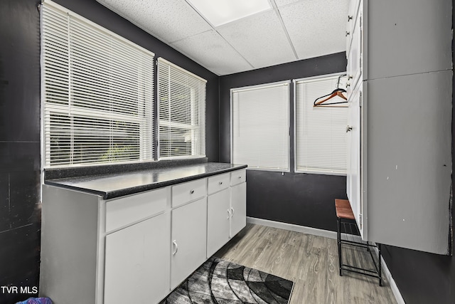 kitchen featuring a drop ceiling, white cabinetry, and light hardwood / wood-style flooring