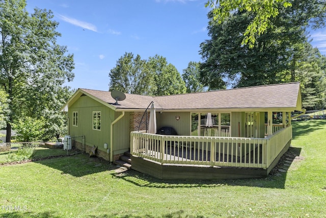 rear view of house with a wooden deck and a lawn