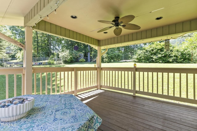 wooden terrace featuring a lawn and ceiling fan