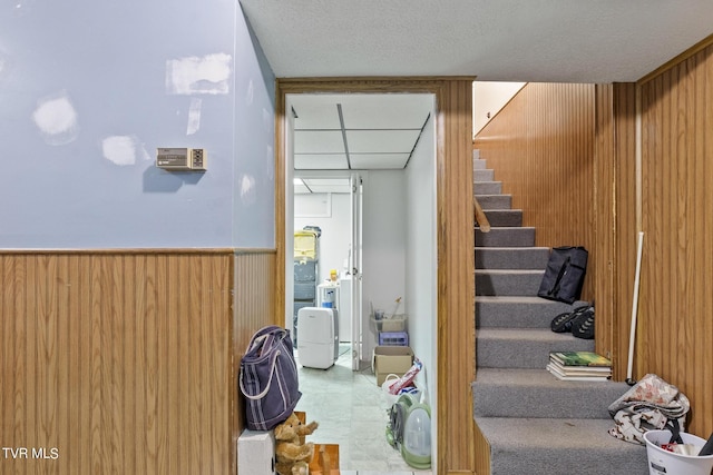 stairs featuring a textured ceiling and wood walls