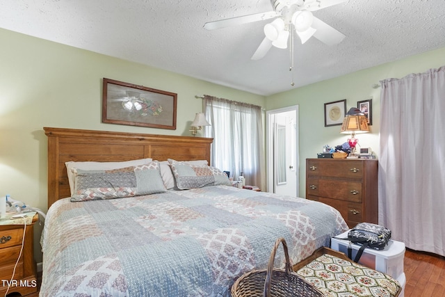 bedroom with hardwood / wood-style flooring, ceiling fan, and a textured ceiling