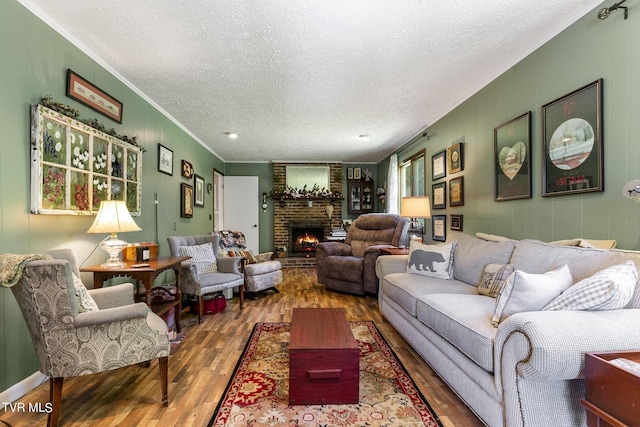 living room with a brick fireplace, crown molding, wood-type flooring, and a textured ceiling