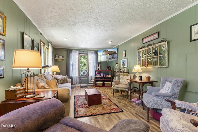 living room with hardwood / wood-style flooring, ornamental molding, and a textured ceiling