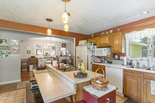 kitchen with a kitchen island, pendant lighting, sink, white appliances, and a textured ceiling