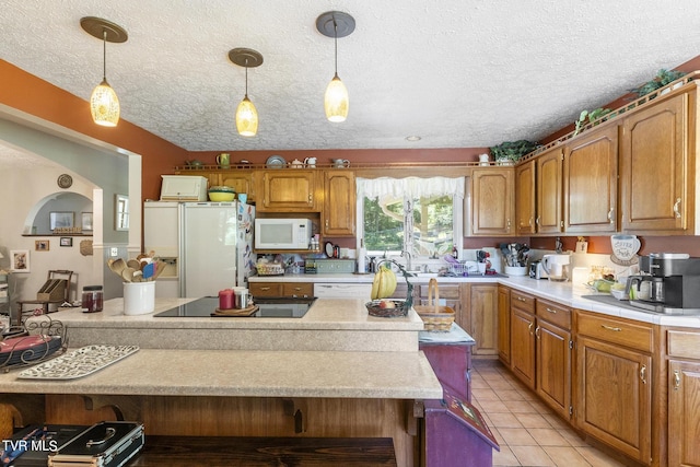 kitchen featuring pendant lighting, sink, white appliances, a textured ceiling, and light tile patterned flooring