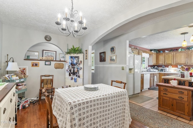 dining room with an inviting chandelier, light hardwood / wood-style floors, and a textured ceiling