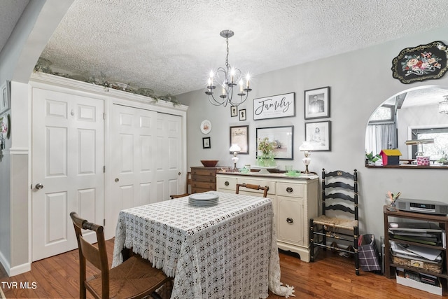 dining room with hardwood / wood-style flooring, an inviting chandelier, and a textured ceiling