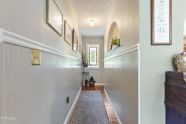 corridor with wood-type flooring and a textured ceiling