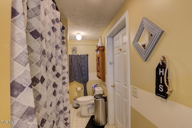 bathroom with tile flooring, toilet, and a textured ceiling