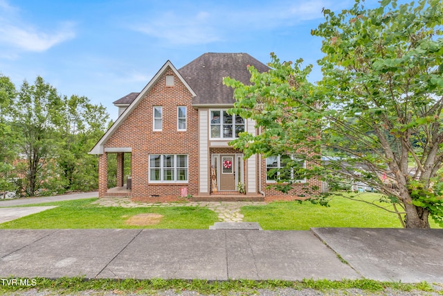 view of front of house featuring roof with shingles, a front yard, and brick siding