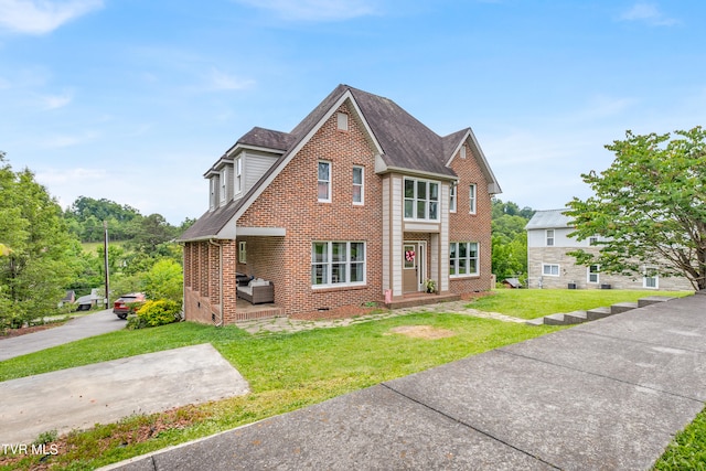 view of front facade featuring brick siding, a front yard, and a shingled roof