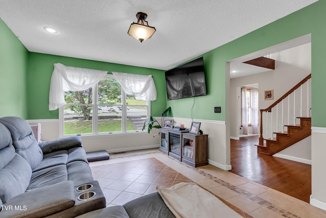 tiled living area with stairway, visible vents, a textured ceiling, and baseboards