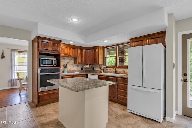 kitchen featuring stainless steel appliances, tasteful backsplash, a sink, and a healthy amount of sunlight