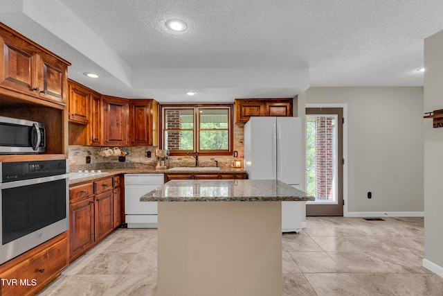 kitchen featuring stone counters, a center island, a sink, stainless steel appliances, and backsplash