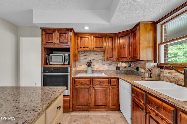 kitchen featuring tasteful backsplash, appliances with stainless steel finishes, a sink, and a textured ceiling