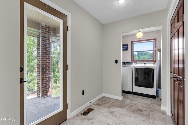 laundry room featuring visible vents, baseboards, laundry area, a textured ceiling, and washing machine and clothes dryer