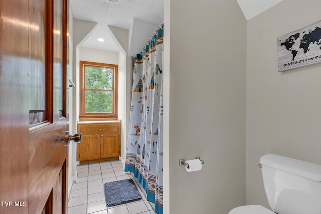 full bath with toilet, a textured ceiling, a shower with curtain, and tile patterned flooring