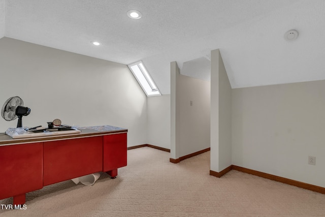 additional living space with vaulted ceiling with skylight, baseboards, light carpet, and a textured ceiling