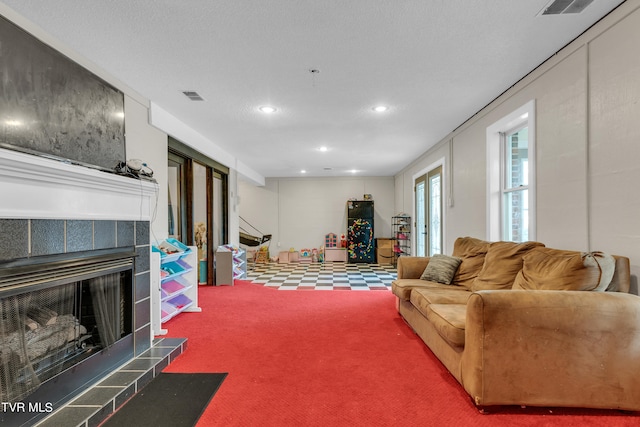 living area featuring visible vents, recessed lighting, stairs, carpet flooring, and a tile fireplace