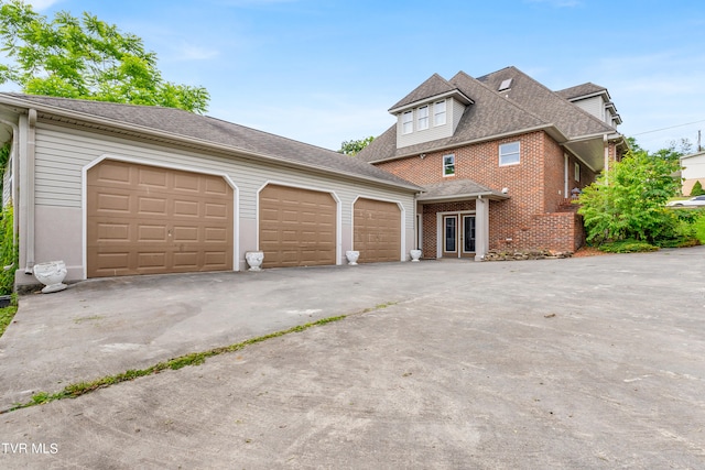 view of front facade with concrete driveway, roof with shingles, brick siding, and a garage