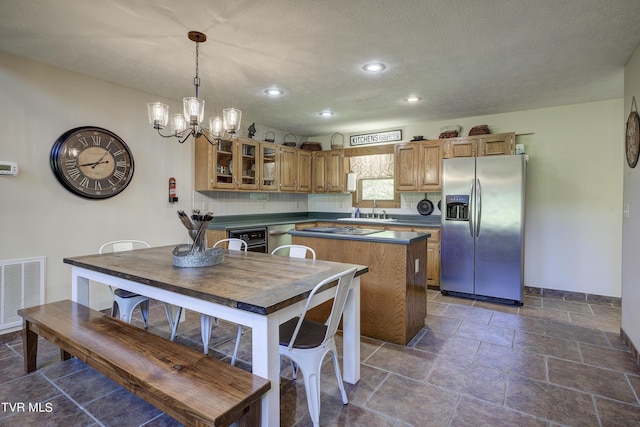 kitchen with a center island, stainless steel appliances, a notable chandelier, a textured ceiling, and decorative light fixtures