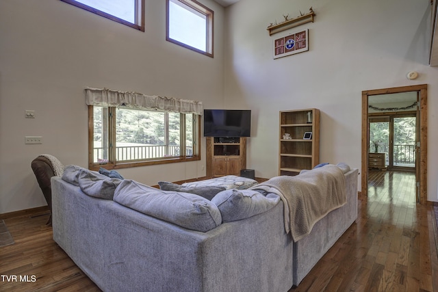 living room featuring plenty of natural light, dark wood-type flooring, and a high ceiling